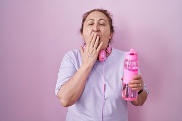 Sticker - Senior woman wearing sportswear and headphones bored yawning tired covering mouth with hand. restless and sleepiness.