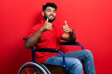 Poster - Arab man with beard sitting on wheelchair success sign doing positive gesture with hand, thumbs up smiling and happy. cheerful expression and winner gesture.