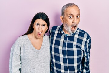 Wall Mural - Hispanic father and daughter wearing casual clothes in shock face, looking skeptical and sarcastic, surprised with open mouth