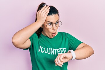 Poster - Young hispanic woman wearing volunteer t shirt looking at the watch time worried, afraid of getting late