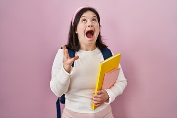 Poster - Woman with down syndrome wearing student backpack and holding books angry and mad screaming frustrated and furious, shouting with anger. rage and aggressive concept.