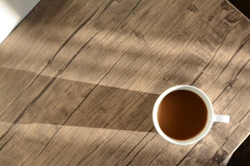 Wall Mural - Cup of coffee on wooden table in morning, top view. Space for text