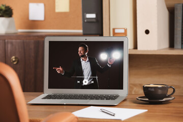 Wall Mural - Laptop with performance of motivational speaker on wooden table indoors