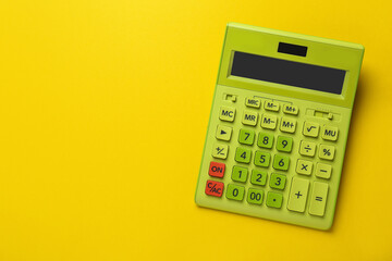 Green calculator on yellow background, top view. Space for text