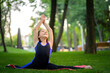 © Roman - a little girl is engaged in meditation and stretching in the park. She sits in a split and stretches her arms up.