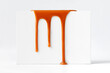 canvas print picture - Dripping caramel drops of sweet caramel sauce on white podium on white background.  Melted caramel sauce drip, drops of sweet liquid toffee.