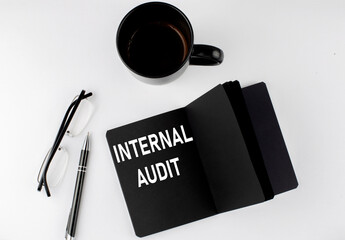 Poster - INTERNAL AUDIT written text in small black notebook with coffee , pen and glasess on white background. Black-white style