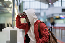 Sad Anxious Black Guy Traveler Feeling Frustrated Because Of Flight Cancellation, Upset African Male Passenger Arrived At Airport Too Late, Disappointed Man Standing Near Check-in Desk, Soft Focus