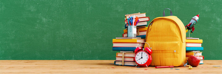 yellow school bag with books and accessory on empty green chalkboard. back to school concept backgro