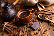 ceramic brown cup and with black coffee and grains on wooden background still life