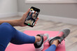 © New Africa - Woman having workout with personal trainer via smartphone at home, closeup