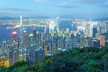 Wall Mural - Beautiful city skyline of Hong Kong at night, viewed from top of Victoria Peak, with dazzling lights of crowded modern skyscrapers by Victoria Harbour & Kowloon area across seaport in blue twilight