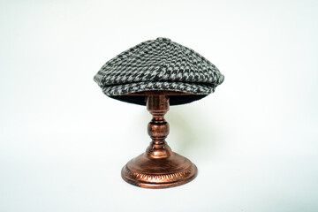 Wall Mural - Detail of a classic eight-panel newsboy hat, in black and white pattern herringbone tweed fabric set against a bronze head mannequin on a white background