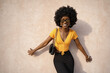 © fotofabrika - Happy African young woman with afro hair wearing stylish sunglasses posing against beige wall