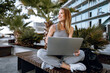 © fotofabrika - Young beautiful casual woman working on a laptop sitting on the bench in the street
