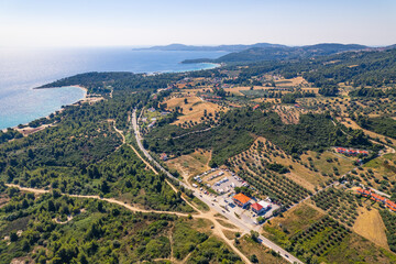 Drone aerial daytime shot of green area and seashore with turquoise water. Few houses with orange rooftops. Beautiful sunny weather. High quality photo