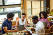 © chika_milan - A group of casual businesspeople is sitting in a restaurant for a meeting, discussing a project while having dinner.