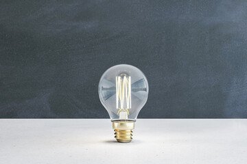 Wall Mural - Close up of illuminated light bulb with filament on blackboard wall background. New idea and innovation concept. 3D Rendering.