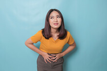 Young Asian Woman With Arms On Stomach And Bending Over With Stomachache Expression