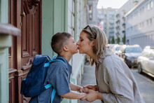 Mother Kissing Her Young Son On The Way To School, And A Mother And Boy Say Goodbye Before School, Back To School Concept.