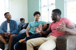 © WavebreakMediaMicro - Multiracial young male friends talking while relaxing on armchairs in living room, copy space