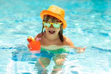 Child drink cocktail in swimming pool. Active healthy lifestyle, swim water sport activity on summer vacation with child. Fashion summer kid boy in hat and sunglasses.