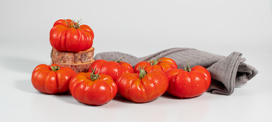 A group of Costoluto big tomatoes on a grey background, textile, space for text