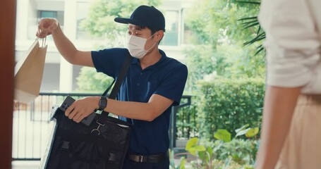 Wall Mural - Young Asian delivery man wear mask in blue navy uniform carry case box knock door home online shopping paper bag to woman in front of door lady scan QR code payment on smartphone at house concept.