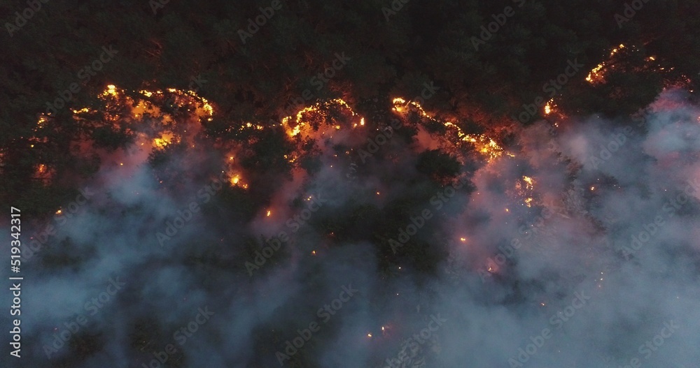 Aerial panoramic view of a forest fire at night, heavy smoke causes air ...