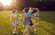 canvas print picture Happy kids playing tag in the park. Group of joyful, excited children running on green lawn, trying to catch each other, enjoying good weather, and having great time together. Summer vacation concept