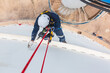 © chitsanupong - Focus top view male worker down height tank roof rope access safety inspection of thickness storage tank gas