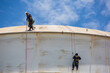 © chitsanupong - Male two worker down height tank roof rope access safety inspection thickness weld of storage tank gas