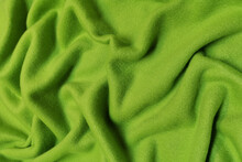 Green Fleece Crumpled Or Wavy Fabric Texture Background. Abstract Linen Cloth Soft Waves. Wool Fabric. Smooth Elegant Luxury Cloth Texture. Concept For Banner Or Advertisement.