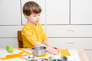 Mom, time to eat! The child prepares toy food in the toy kitchen. Kid imitate adult responsibilities. Activities at home. A game that encourages creativity. Felt pasta.