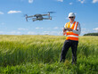 © Grispb - Geodetic technologies. Man surveyor next to green field. Geodetic survey with help of drone. Surveyor reflective vest. Topographic survey of area from drone. Drone for surveyor purposes