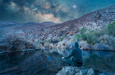 Wall Mural - silhouette of a person meditating on a lagoon at night with stars in the background