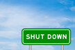 Green color transportation sign with word shut down on blue sky with white cloud background