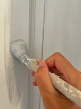Close-up Of A Woman Painting A Doorframe With Grey Paint