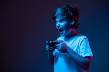 Wall Mural - A boy with emotions plays with a joystick. The guy is holding a joystick in neon light.