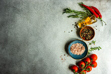 Overhead View Of Salt, Pepper, Olive Oil, Cherry Tomatoes, Rosemary And Chilli Peppers On A Table