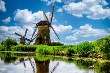 Two Windmills Along A Riverbank, Holland