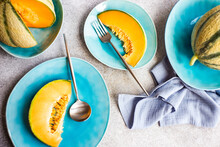 Overhead View Of Cantaloupe Melons And Slices Of Melon On Plates