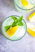 Overhead View Of Two Mojito Cocktails On A Table With Fresh Mint And Lemon