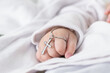 close-up detail of a baby's hand at his baptism, holding a christian cross. catholic baptism in latin church. caucasian baby with a silver cross clutched in his right hand. religion concept.