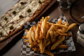 pizza crijiente con muzzarella, salsa de tomates, oregano y aceitunas junto a plato de papas fritas