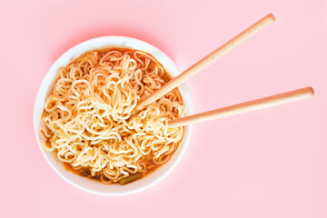 Wall Mural - A plate with ready ramen and wooden sticks on pink background, view from above