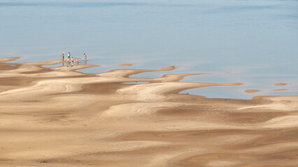 Wall Mural - Summer minimal landscape, distant view of people enjoying the beach of a river in El Palmar National Park, Entre Rios, Argentina. Simple image for the concept of vacations and enjoyment of nature.