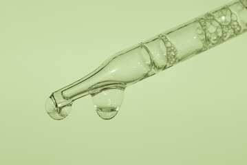 Pipette with liquid essence on a light green background With air inside. This is the consistency of micellar water. The concept of an extract for cosmetic purposes. High quality photo