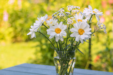 In A Glass Vase With Water On The Table, A Bouquet Of Delicate White Daisies And Pearls.