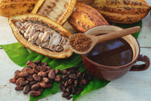View From Above, Cup Of Chocolate Drink With Fresh Cocoa Fruits, Pile Cocoa Powder In Spoon On Cup, Cutting Cocoa Pods In Half Show The Inside Of Raw Cacao Beans, On White Wooden Table